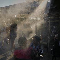Des personnes passent devant un brumisateur pour se rafraîchir pendant une chaude journée dans le quartier de Monastiraki à Athènes.
