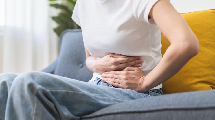 Sick asian young woman in pain, hand holding belly, stomach pain from food poisoning, girl hurt abdomen ache and digestive problem, gastritis or diarrhea. Health care inflammation, abdominal problem Frauengesundheit