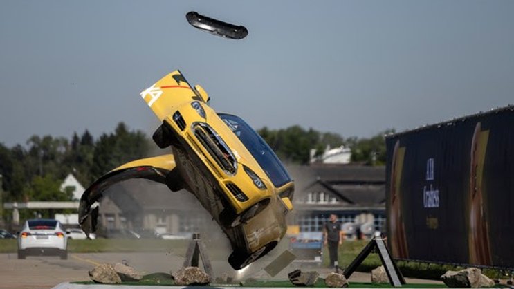 Ein Tesla kollidiert mit einem Kreisel und überschlägt sich bei einem simulierten Unfall.