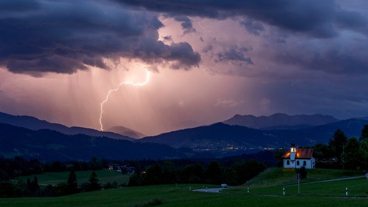 Blitze entladen sich über den Alpen während eines aufziehenden Gewitters am Abend im bayerischen Scheidegg.